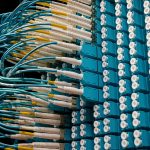 Cabos de fibra óptica conectados a um painel azul em um data center