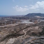 Vista aérea de um extenso parque eólico em uma paisagem seca e árida.