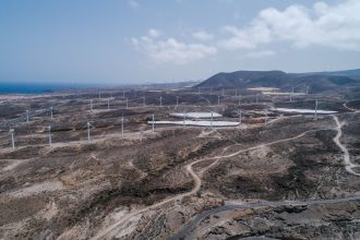 Vista aérea de um extenso parque eólico em uma paisagem seca e árida.
