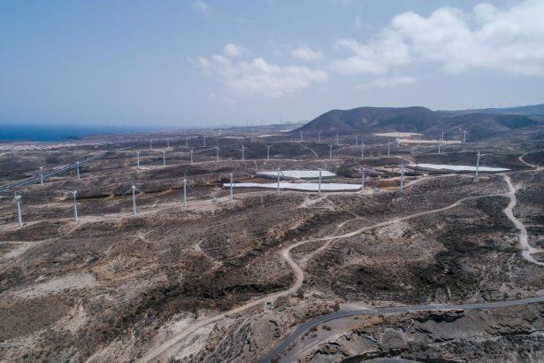 Vista aérea de um extenso parque eólico em uma paisagem seca e árida.