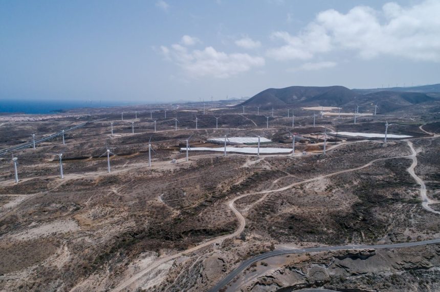Vista aérea de um extenso parque eólico em uma paisagem seca e árida.