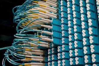 Cabos de fibra óptica conectados a um painel azul em um data center