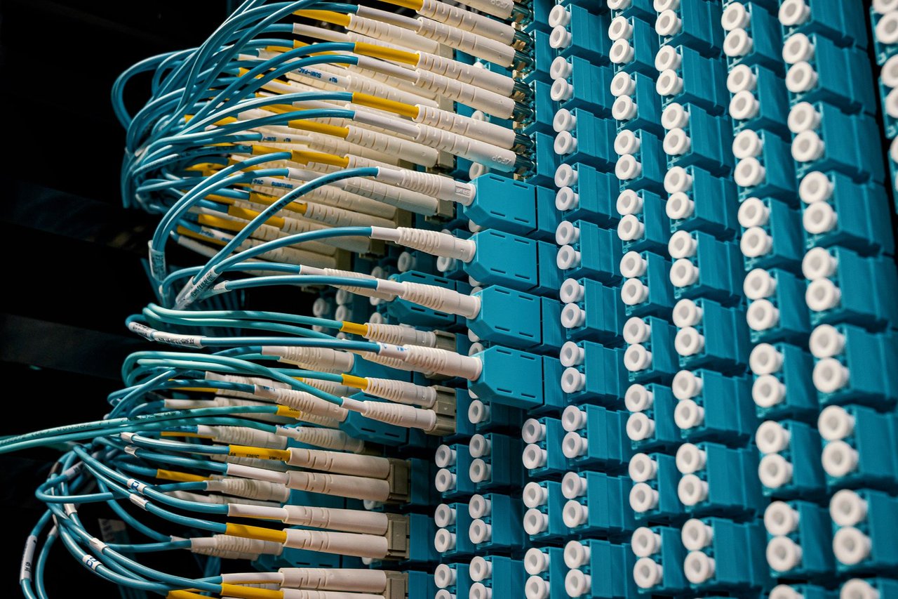 Cabos de fibra óptica conectados a um painel azul em um data center